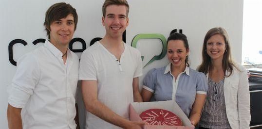 Süß und in Magenta: Patrick Crüger (l.) und Laurita Mroß (r.) von der Deutschen Telekom überreichen den Loftbewohnern Tonia Schneider und Tim Fahrendorff einen Begrüßungskuchen.