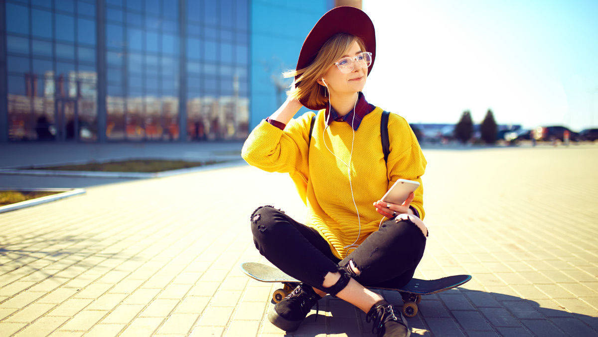 Frau mit Skateboard surft auf ihrem Handy