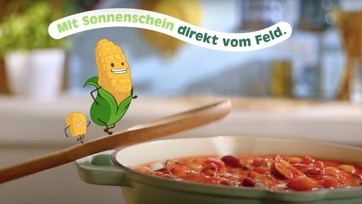 Ein animierter Maiskolben springt in eine Pfanne, darüber steht "Mit Sonnenschein direkt vom Feld".