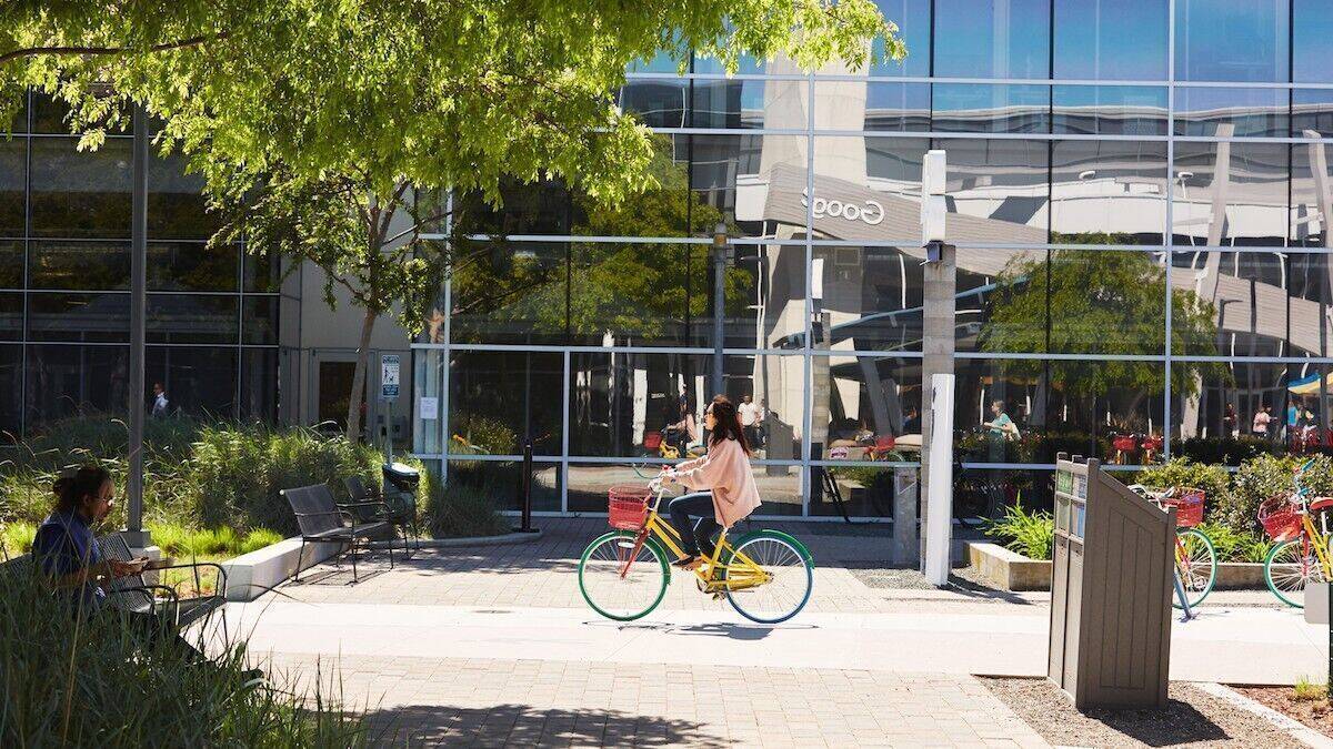 Eine Frau mit Brille fährt auf dem Gelände von Google Fahrrad.