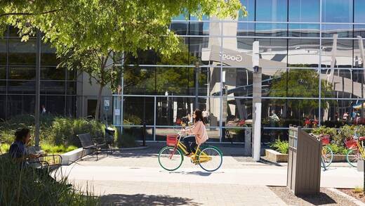 Eine Frau mit Brille fährt auf dem Gelände von Google Fahrrad.
