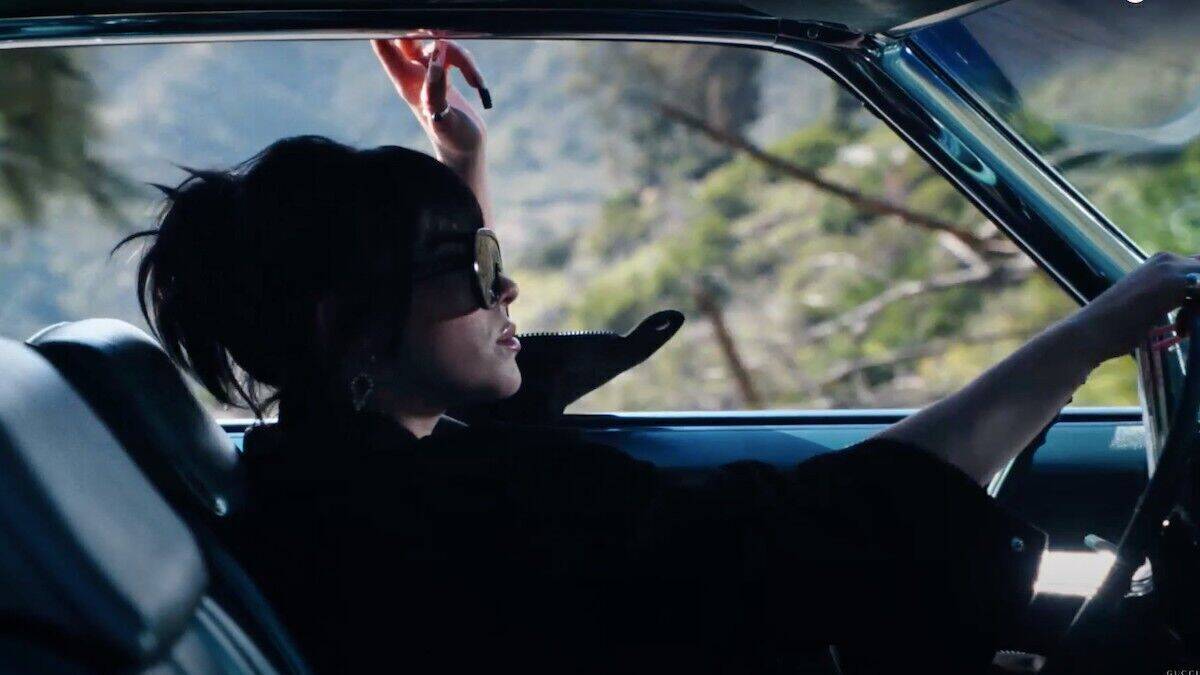 Billie Eilish fährt in einem Oldtimer und trägt dabei eine Gucci-Sonnenbrille. 