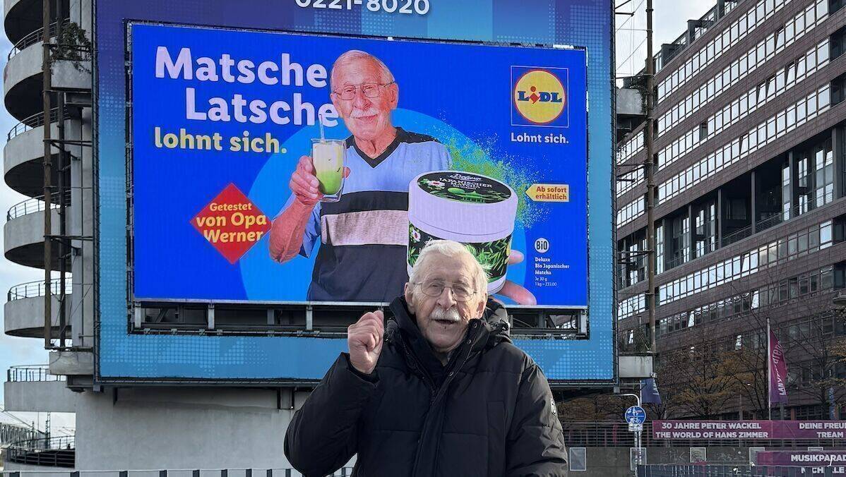 Opa Werner kann es nicht fassen: Ein digitales Plakat von ihm und seinem "Matsche-Latsche"-Test hängt in Köln an der Lanxess-Arena.