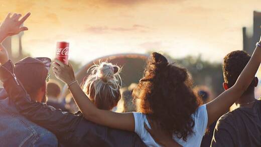 Eine Gruppe junger Menschen auf einem Festival, eine Frau hält eine Dose Coca Cola. 