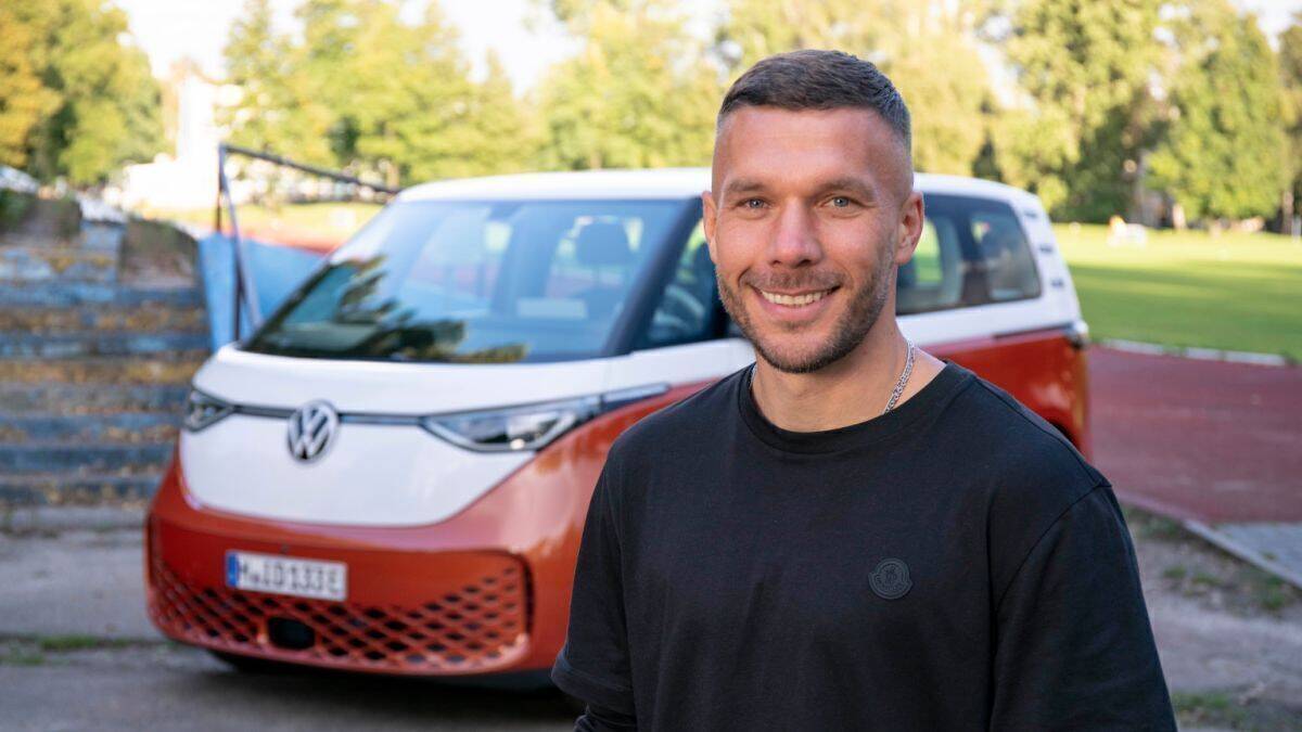 Lukas Podolski posiert vor dem Elektrobulli ID Buzz