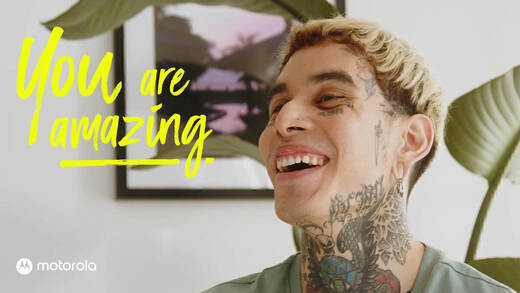 Ein Foto von einem lachenden Mann mit vielen Tattoos, links neben ihm der Schriftzug "You are amazing". 
