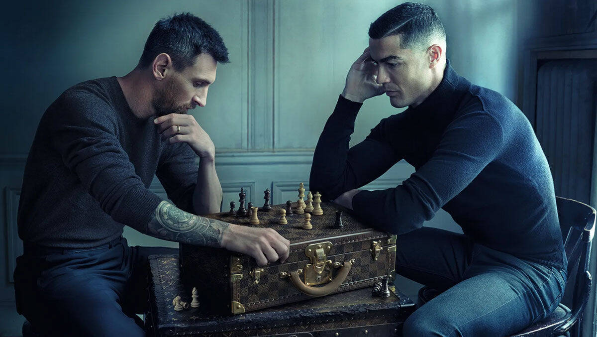 Lionel Messi und Cristiano Ronaldo spielen Schach auf einem Koffer von Louis Vuitton. 