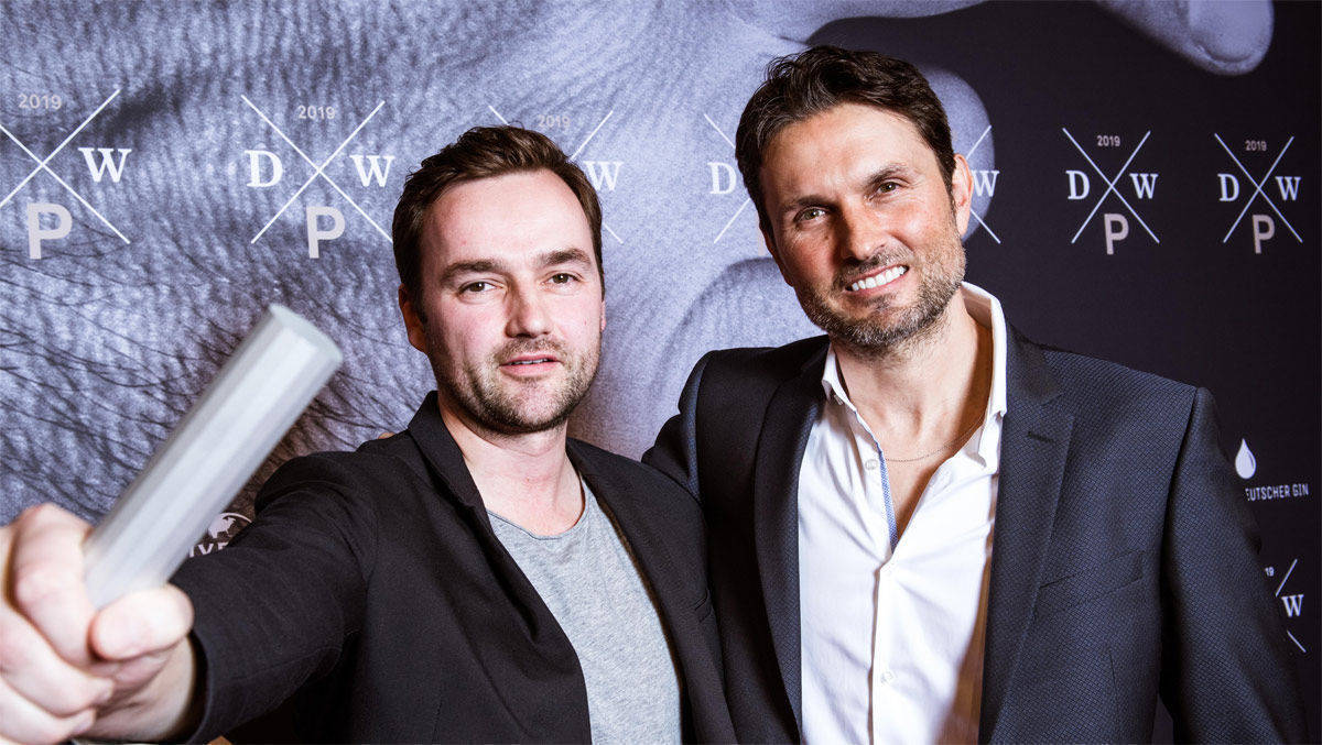 Justin Mundhenke (links) nimmt für Tempomedia  den Deutschen Werbefilmpreis für die beste Regie entgegen. Preisträger ist Alex Feil. Rechts: Laudator Simon Verhoeven.