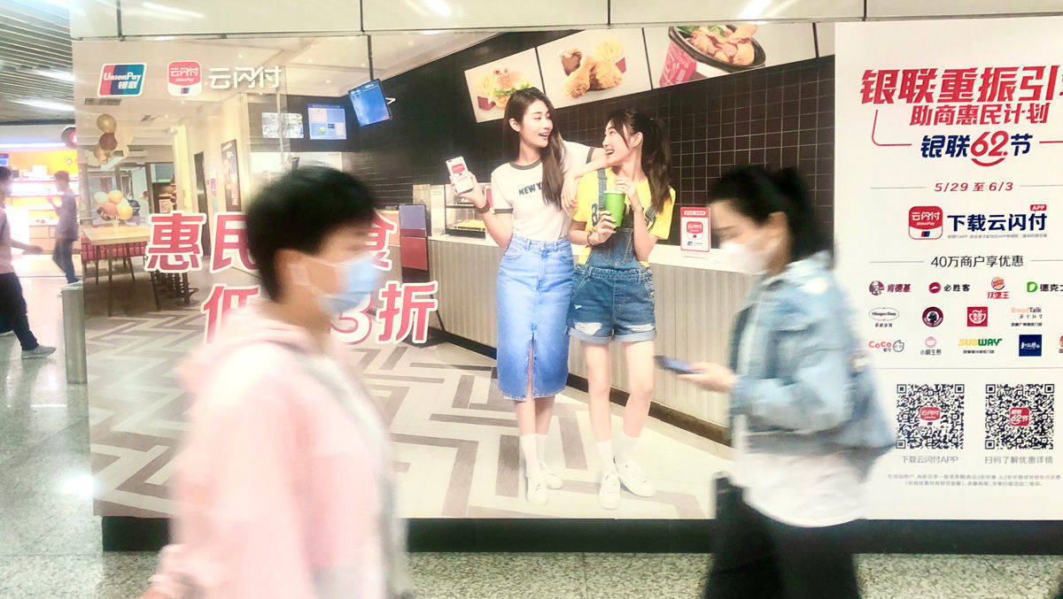 Parallelwelten: Die Werbung ist Covid-frei, das wahre Leben ist es nicht. Metro im Mai in Shanghai.