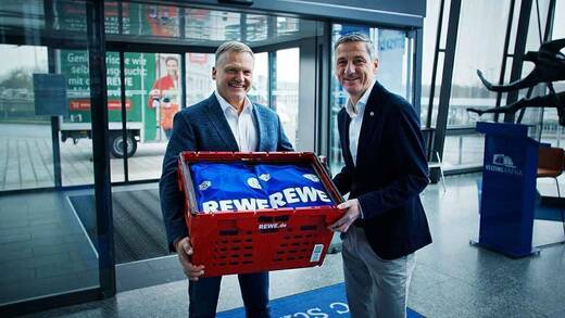 Peter Maly von Rewe liefert neue Trainingskleidung an Bernd Schröder von Schalke aus.