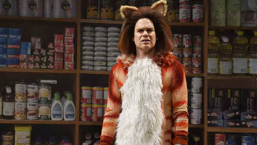 Michael C. Hall stand für die einmalige Show "Skittles Commercial: The Broadway Musical" auf der Bühne vor Regalen voller Markenartikel.