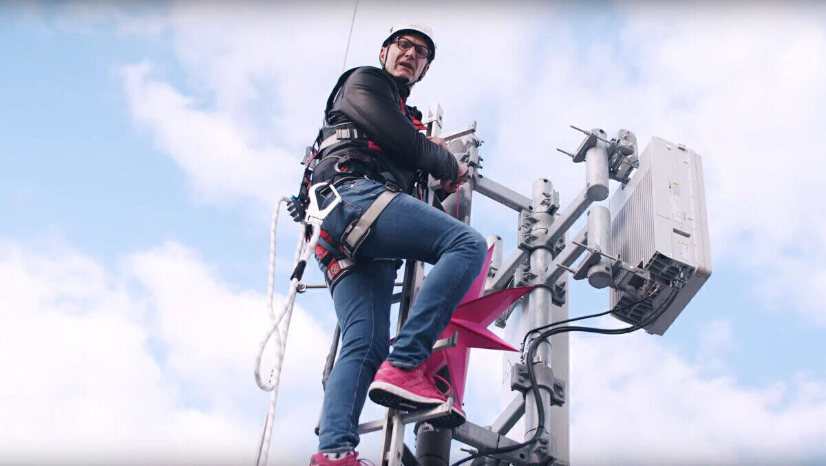 Telekom-Chef Tim Höttges montiert einen Weihnachtsstern auf einer 5G-Antenne.
