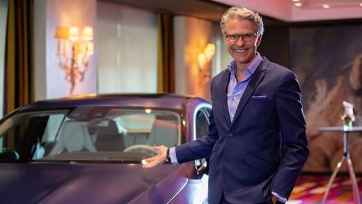 Michael Sandvoss, Moderator der Watches & Jewellery Luxury Conference vor einem Mercedes AMG GT 63 S