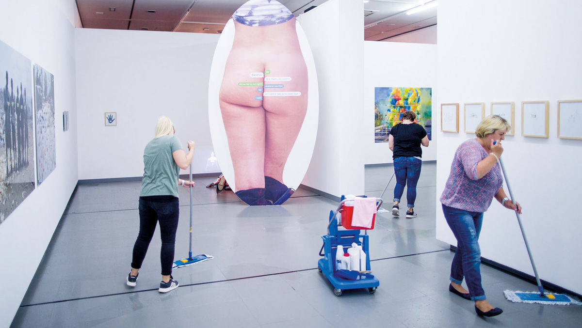 1. Platz in der Kategorie "Kultur": Reinigungskräfte putzen im Juni in Düsseldorf eine Ausstellung, zu dem auch das Werk "Text Butt" (2015) des in New York lebenden Schweizer Künstlers Olaf Breuning gehört.