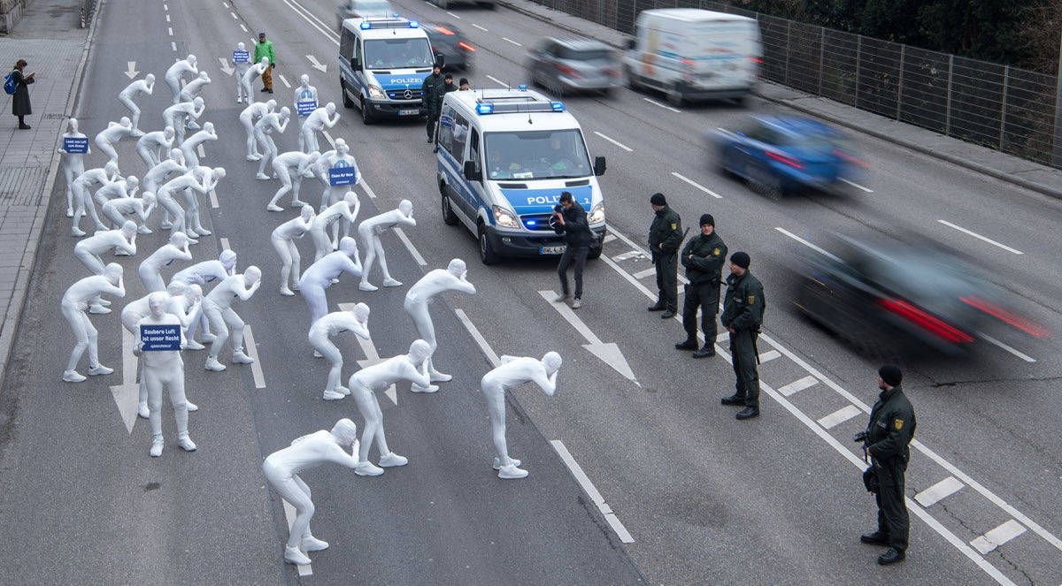 Menschen in Ganzkörperanzügen demonstrieren gegen Luftverschmutzung durch Diesel. Foto des Jahres der Kategorie News.