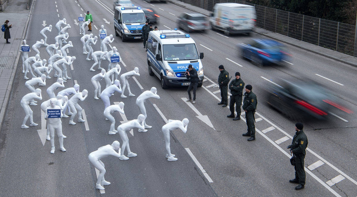 Menschen in Ganzkörperanzügen demonstrieren gegen Luftverschmutzung durch Diesel. Foto des Jahres der Kategorie News.