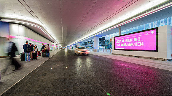 Magenta von rechts und von links: Am neuen Terminal 1 am Flughafen Frankfurt hüllt ein Digital Brand Space die Passanten ein.
