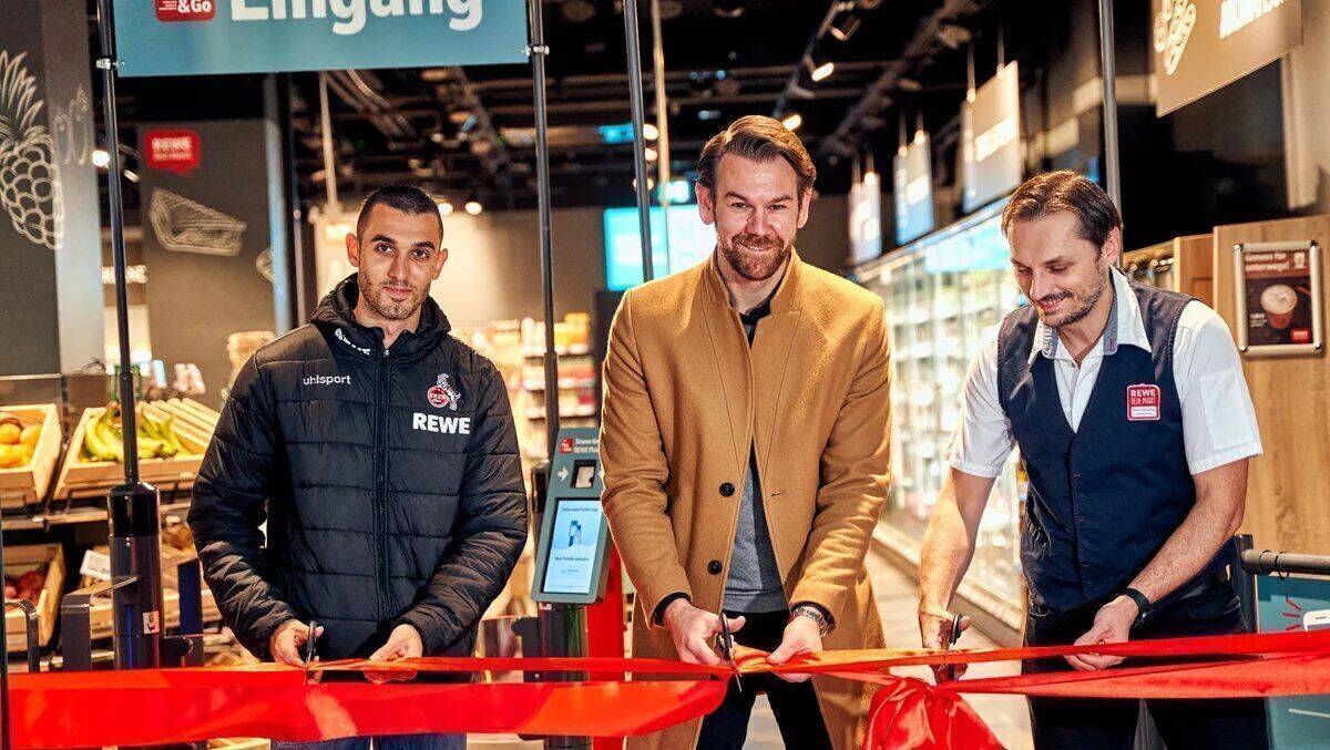 Ellyes Skhiri (l.) und Thomas Kessler (Mitte) vom 1. FC Köln geben mit Rewe-Marktmanager Darius Malucha den Startschuss für den ersten Pick&Go-Markt.